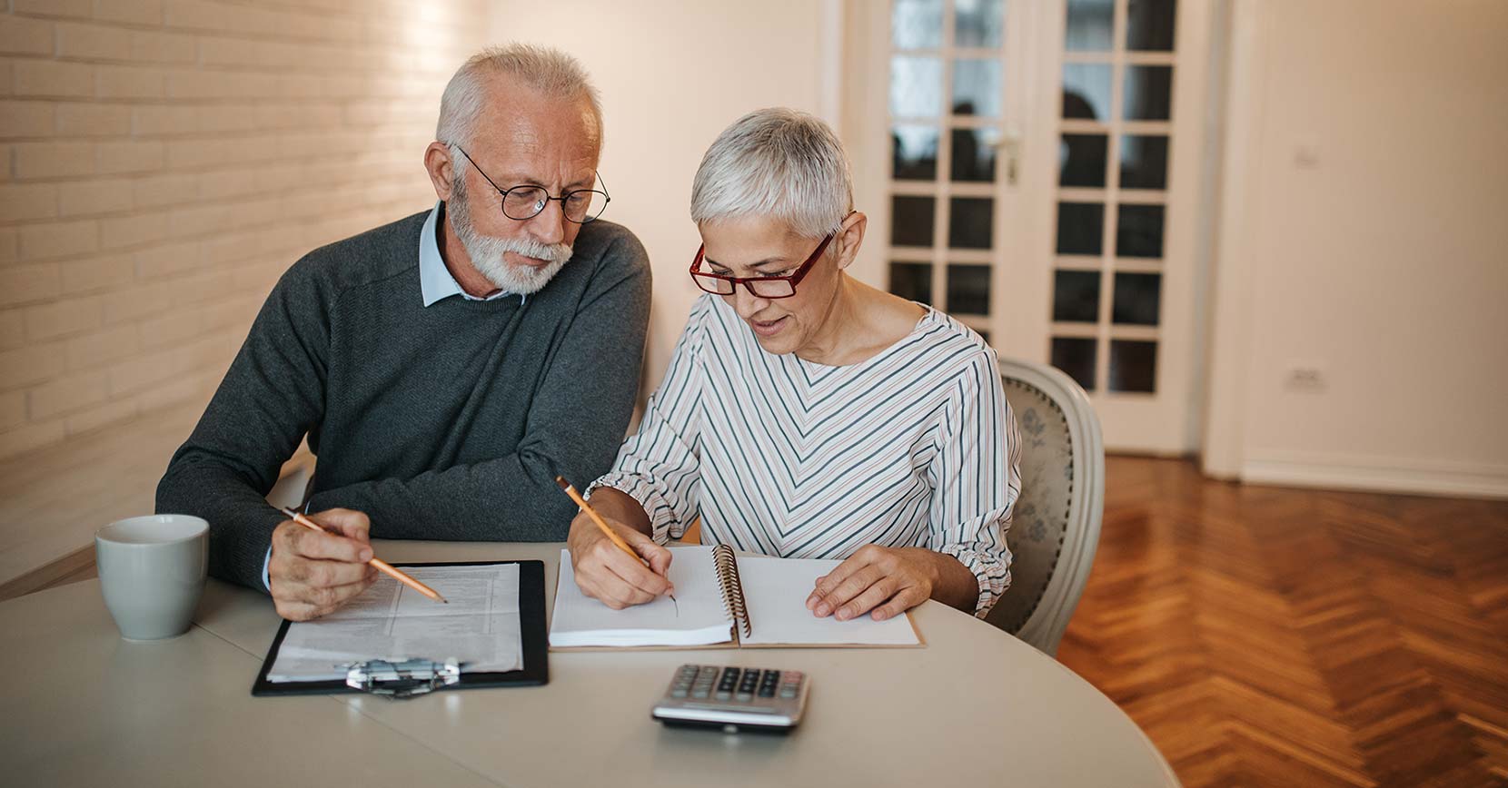 kuvassa vanhempi pariskunta pöydän ääressä. artikkeli käsittelee käänteistä asuntolainaa